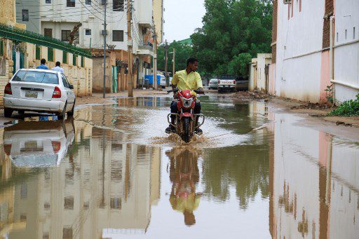 Un hombre conduce una motocicleta por una calle inundada luego de fuertes lluvias en la capital de Sudán, Jartum, el 13 de agosto de 2022.