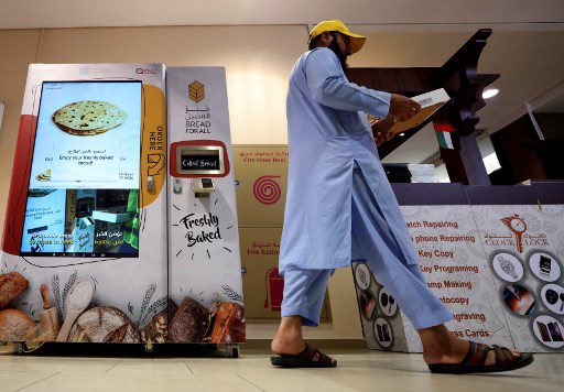 Un hombre sostiene una caja que recogió de una máquina expendedora que ofrece pan gratis, en Dubái, el 22 de septiembre de 2022.