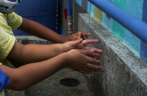 Un grupo de niños se lavan las manos en un grifo múltiple que suministra agua de lluvia filtrada en el preescolar Fermín Toro, beneficiario del programa 