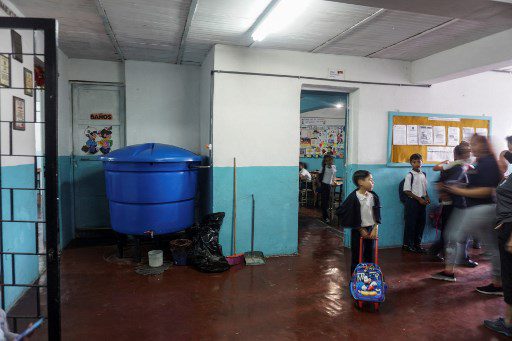 Los alumnos se paran cerca de un tanque de captación de agua de lluvia utilizado para abastecer de agua a los baños del preescolar Fermín Toro, beneficiario del programa "Lata de Agua", en el populoso barrio de Petare en Caracas