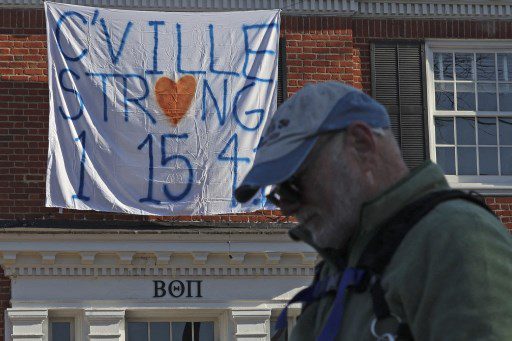 Un peatón se para frente a una casa de fraternidad con una pancarta que recuerda a tres jugadores de fútbol de la Universidad de Virginia asesinados durante un tiroteo nocturno en la universidad el 14 de noviembre de 2022