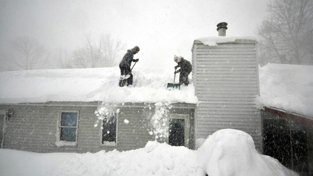 Hombres remueven la nieve de techos y calles