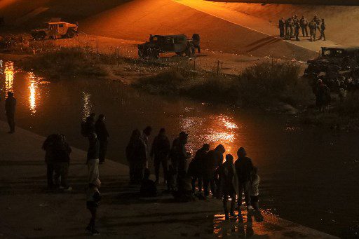 Migrantes calientan alrededor de una fogata a orillas del Río Grande, donde agentes de la Guardia Nacional de Texas impiden que se entreguen a agentes de la Patrulla Fronteriza en el Sector El Paso, luego de haber cruzado el Río Bravo/Río Grande desde Ciudad Juárez, estado de Chihuahua, México. Foto AFP - Referencial