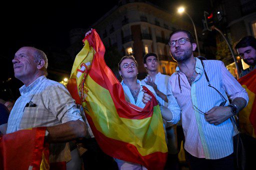 Los partidarios sostienen la bandera nacional de España mientras esperan los resultados de las elecciones frente a la sede del líder y candidato del conservador Partido Popular Alberto Núñez Feijoo en Madrid el 23 de julio de 2023