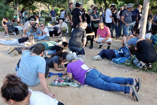 Los dolientes se agachan para cubrirse al escuchar sirenas que advierten de la llegada de cohetes durante el funeral de Tom Godo, asesinado durante el ataque de militantes palestinos de Hamas al Kibbutz Kisuffim la semana pasada, en el Kibbutz Naan, cerca de Tel Aviv, el 13 de octubre de 2023.